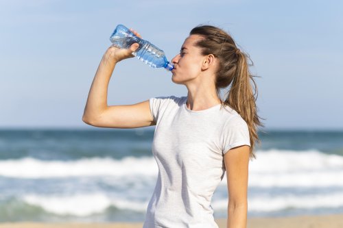 side-view-woman-staying-hydrated-beach-workout.jpg